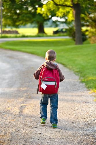 boy walking wearing a red backpack