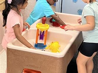 Three children playing at a water table