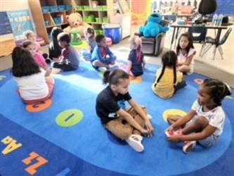 A kindergarten class sitting on the carpet in pairs sharing